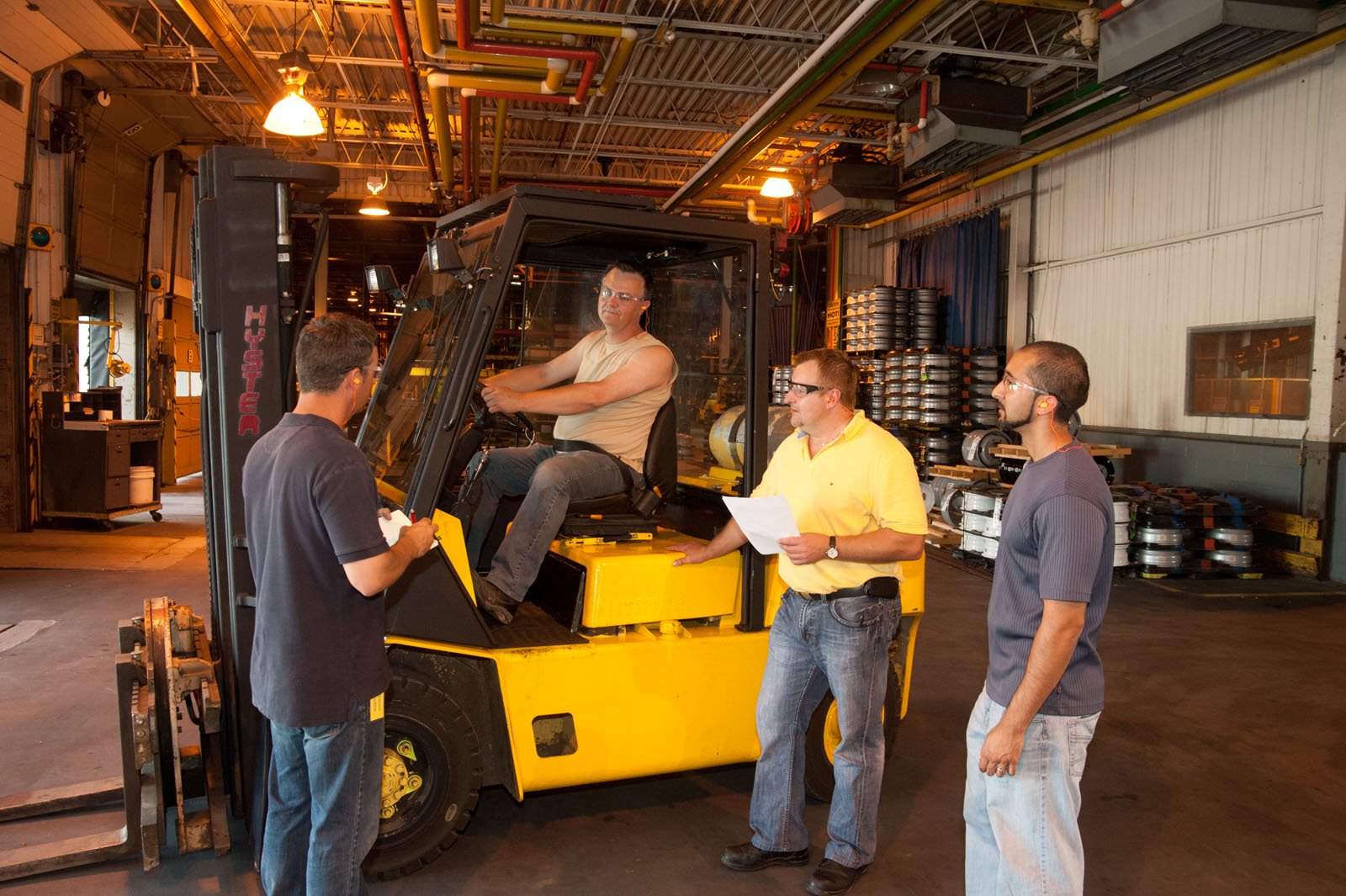 Safe Operation of a Lift Truck Training. Group of males standing around a lift truck talking.