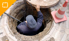 Confined Space Awareness. Man climbing out of sewer.