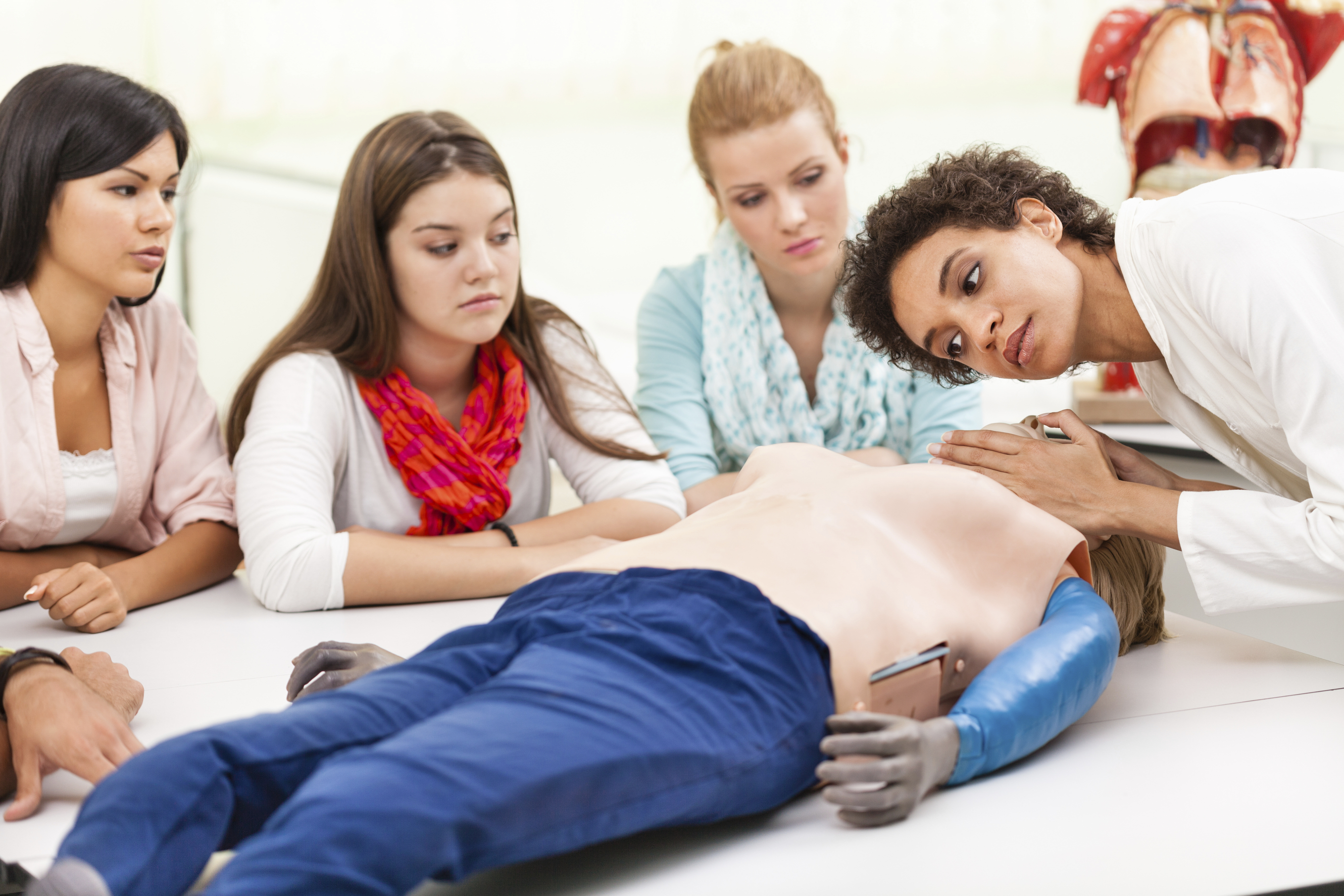 Female instructor demonstrating chest compressions on a CPR dummy.