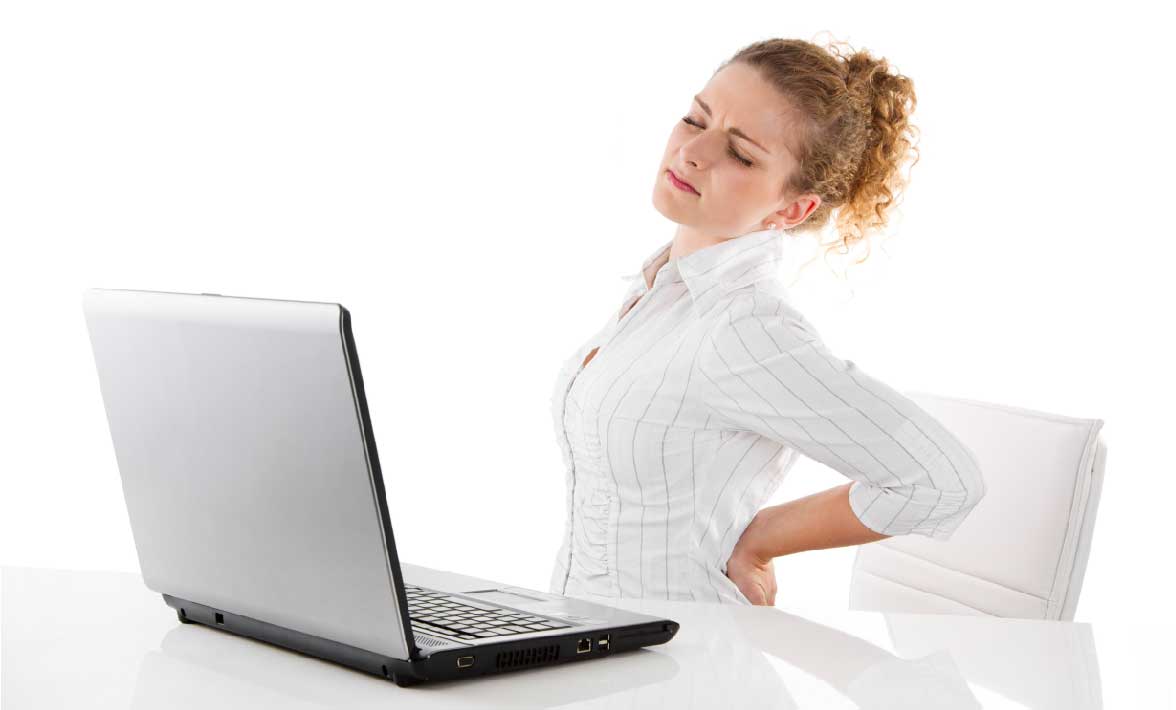 woman sitting at a desk with her hand on her back looking uncomfortable