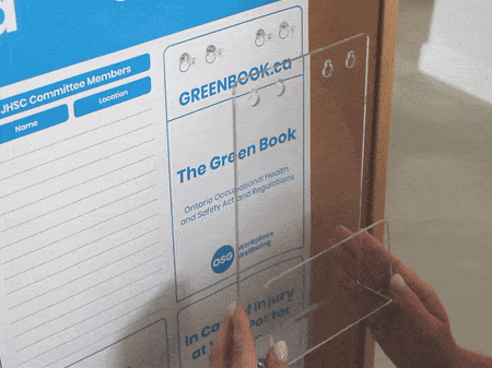 Clear plastic Green Book Holder being places onto health and safety board