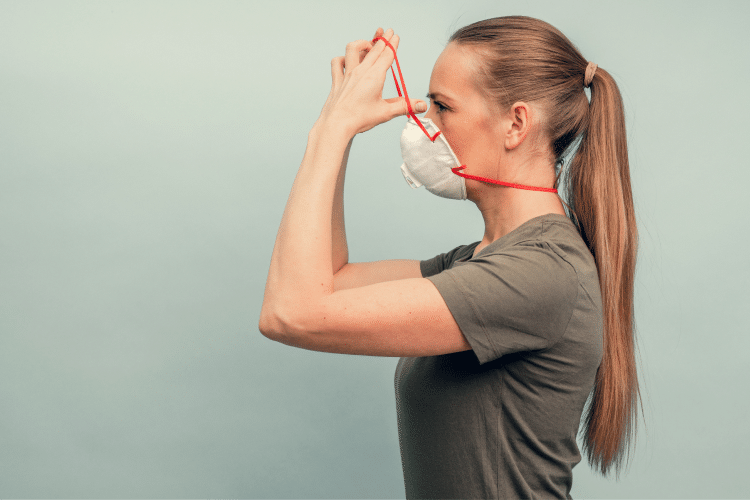 A woman is putting on a protective mask