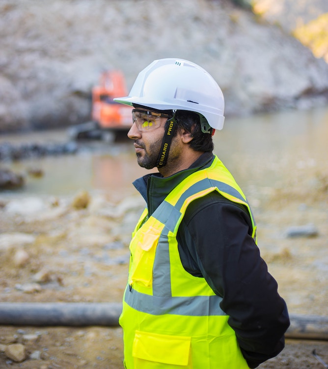 Man wearing PPE standing outside looking to the left attentively