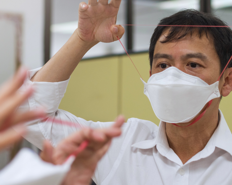 Asian man testing respiratory system with N-95 surgical mask to check if it properly fits the face to wear.